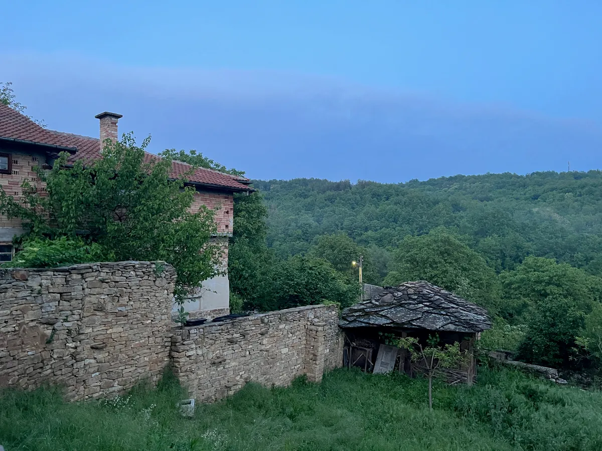 Каменен зид, къщи и горски склон край Старилковци